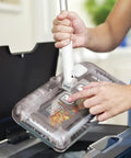 User operating No Fuss Grab And Go Cordless Floor Sweeper with swivel head over a dust bin for easy cleanup.