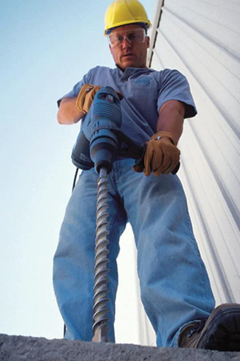 Worker using Fixed-Depth Bit MDPL050DIA for Three Eighths Inch Drop-In Anchors on concrete wall, ensuring precision depth control.