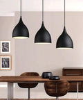 Dark Antique Farmhouse Pendant Light with Single Hanging Shade above a wooden dining table in a modern setting.
