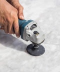 Close-up of a hand using a die grinder with Five Pack Disc Pad Holder Set With Quick Change 1 Inch 2 Inch 3 Inch Pads on marble surface.