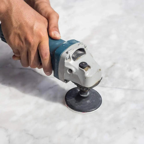 Close-up of a hand using a die grinder with Five Pack Disc Pad Holder Set With Quick Change 1 Inch 2 Inch 3 Inch Pads on marble surface.