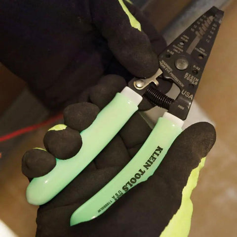 Hands holding Glow In The Dark Grips Wire Stripper And Cutter With Serrated Curve Nose For 10 To 18 AWG Solid And 12 To 20 AWG Stranded Wire Pro Grade Tool Made In USA.