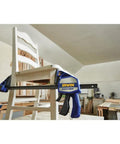 Heavy Duty One Handed Bar Clamp With Quick Change Spreader Removable Swivel Jaws holding a white chair in a workshop.