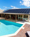 Backyard with an in-ground swimming pool, wooden deck, and house with solar panels on the roof.