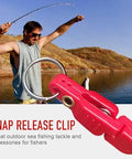 Pink plastic snap release clip for planer board fishing with metal ring, shown in foreground.