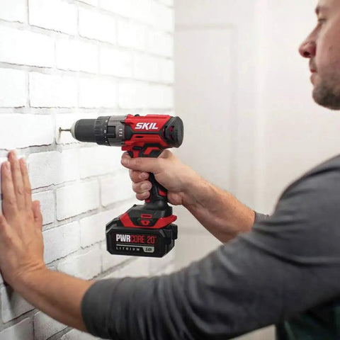 Man using PWRCore 20 Hammer Drill Kit With 2.0Ah Battery And Fast Charger Cordless Go To Drill for drilling a brick wall