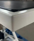 Close-up of the edge of Heavy Duty Electric Dog Grooming Table With Smooth Operator Foot Pedal And Kickass Sturdy X Frame For Easy Height Adjustments And No Sweat Pet Styling In White.