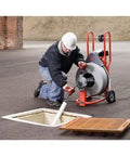 Heavy Hitter Auto Feed Drum Drain Snake Machine With 3 4 Inch C 100 Inner Core Cable in use for clearing pipe blockages.