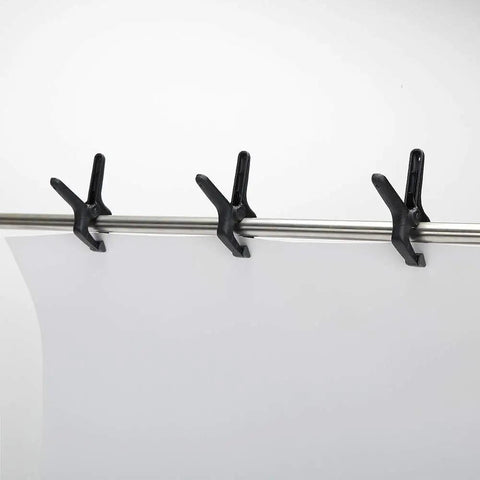 Three black nylon spring clamps from 14 Piece Nylon Spring Clamp Set For Photography, Woodworking And Crafts holding a backdrop.