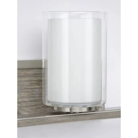 Close-up of clear and etched glass shade on faux wood back plate of Four Light Linear Chandelier In Brushed Nickel