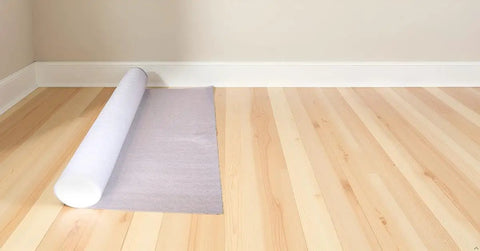 Slick And Tough Foam Underlayment Roll For Laminate And Wood Flooring With Moisture Resistant Barrier laid out on wooden floor.