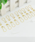Gold metal security pins next to white nylon string ties, part of Top Shelf Hang Tag Fasteners With White Nylon String Ties And Gold Metal Security Safety Pins Bulk Kit For Retail Apparel Display Boutique Clothing Price Cable Accessories.