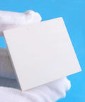 Boron Nitride Ceramic Sheet Pad and Plate for heat proof performance held by a gloved hand, size 150 x 150 x 2 mm.