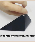 Hand peels triangle-shaped 16 Pack Non Slip Rug Tape For Hardwood Floors And Tiles Double Sided Reusable Gripper Pads.
