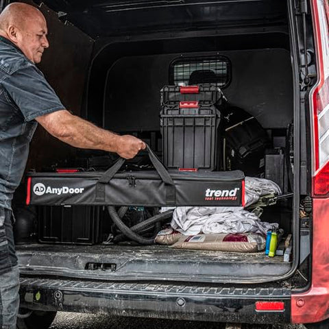 Man loading All-In-One Adjustable Door Hinge Jig Installation Kit For 2 Ft 6 In To 9 Ft Doors into a van, showing the carry case.