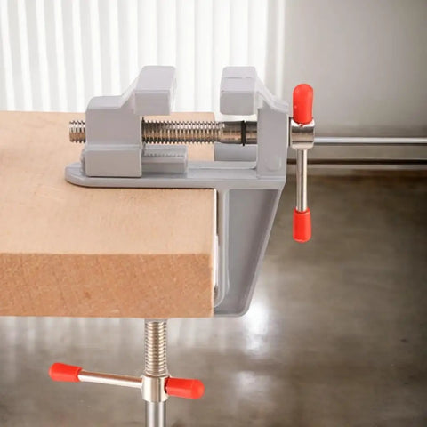 Compact Table Vise For DIY Projects And Home Repairs, Handy Bench Clamp For Woodworking On Your Workbench Or Craft Desk, Lightweight Yet Sturdy Aluminum Vise With Adjustable Jaw And Portable Clamp shown mounted on a wood surface.
