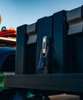Small Stainless Steel Combination Cable Lock For Overland Truck Racks securing a black storage box on a vehicle roof.