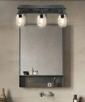Industrial Mason Jar Vanity Light Wall Sconce In Black Finish above bathroom mirror, three light fixture with glass jar shades.