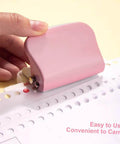 Person using pink Six Hole Puncher For Loose Leaf Notebooks on paper