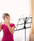 Child playing flute beside Portable Foldable Music Stand For Piano And Violin, Lightweight Metal Sheet Music Holder, adjustable 28-54 inches
