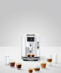 Top Tier Automatic Espresso Machine Bundle In Piano White With Glass Milk Container And Clearyl Smart Filter Cartridge For Seamless One Touch Operation And Premium Daily Grinds with assorted drinks.