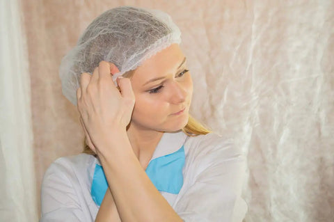 Woman adjusting Disposable Bouffant Hair Caps 21 Inch Head Cover Net For Salon Or Spray Tan Breathable Nonwoven Fabric With Elastic Band