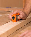 Hand using Green Laser Distance Measure Tool With 200 Foot Range For DIY And Pros, USB Rechargeable on wood surface