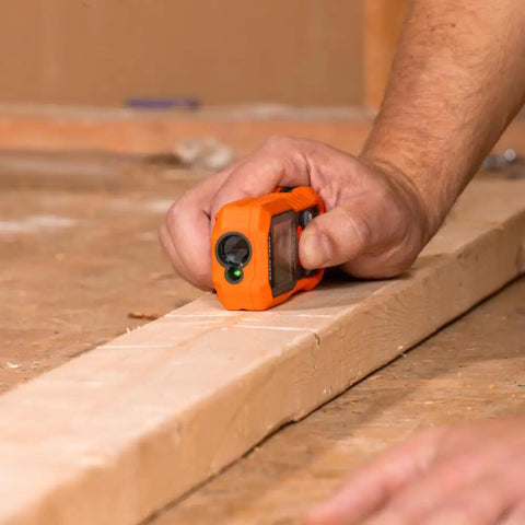 Hand using Green Laser Distance Measure Tool With 200 Foot Range For DIY And Pros, USB Rechargeable on wood surface