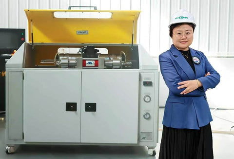 Waterjet cutting machine with yellow lid open; operator in blue blazer and hard hat beside it.