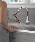 Woman using Xander Single-Handle Chrome Kitchen Faucet With Pull-Down Sprayer Easy Install For 1-Hole Or 3-Hole Sinks