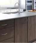 Kitchen island with transitional tapered curved arch drawer handle pull in satin nickel finish 128mm center to center on dark wood cabinets.