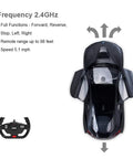 Top view of BMW I8 1:14 Scale Remote Control Car With Open Scissor Doors, Matte Black RC Toy Vehicle with remote shown.