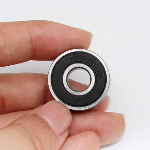 Close-up of a 608-2RS skateboard bearing with black rubber seal, 8x22x7 mm, held between fingers