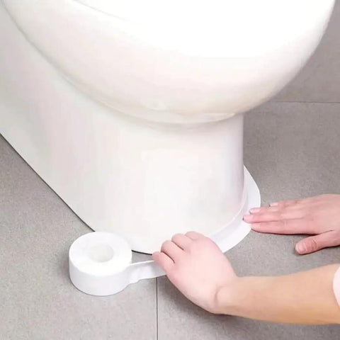 A hand applying Heavy Duty PVC Sealing Tape For Kitchen Sink And Bathroom Waterproof Oil Proof Caulk Strip around a toilet base.