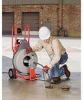 Heavy Hitter Auto Feed Drum Drain Snake Machine With 3 4 Inch C 100 Inner Core Cable in use, clearing a drain blockage.