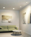 Narrow Frame LED Recessed Downlight illuminating a modern living room with green sofa and abstract wall art.
