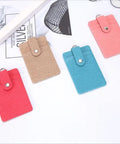 Four colorful fabric card holders with snap button closures, visible in red, beige, blue, and pink.