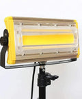 JUDYSSY Led Floodlight 50W 3600Lm Led Outdoor Floodlight mounted on a tripod with a yellow and clear casing.
