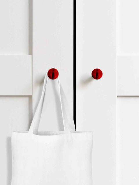 Top Shelf 2 Piece Cabinet Knobs Measuring 1.6 Inch Tall Featuring A Dope Red Matte Finish on white cabinet with tote bag.
