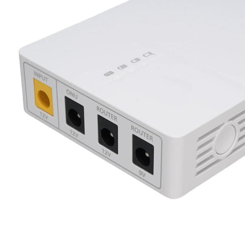 Close-up of Mini UPS Battery Backup For Security Cameras Routers And Networking Gear showing input and output ports for power connection.