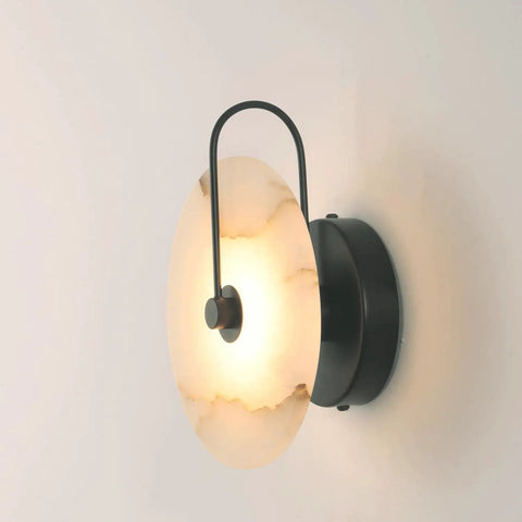 Nordic Style Stone Wall Lamp With Alabaster Finish, Metal Base Indoor Sconce For Living Room Dining Room Hallway Or Study, Cozy Glow Ambient Marble Look Wall Light For Modern Home Decor. Side view of lit alabaster wall sconce with black metal base.