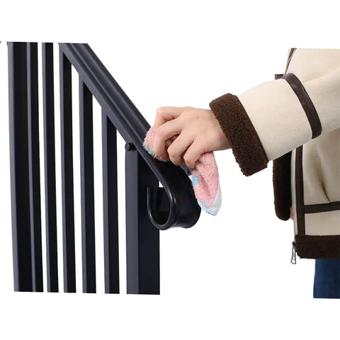 Person cleaning Rock Solid Three Step Outdoor Handrail Featuring Smooth Curved Wrought Iron Frame with cloth for maintenance.
