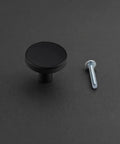 Matte Black Round Cabinet Knobs 2 Pack With Screws, Sleek Modern Drawer Pulls, Durable Alloy Construction, shown with a screw on a table