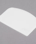 White flexible polypropylene bowl scraper on grey background. Two Flexible Polypropylene Bowl Scrapers That Help You Get Every Last Drop Of Dough Batter Or Icing From Mixing Bowls And Flat Surfaces And Conform To Curves For Mess Free Scraping.