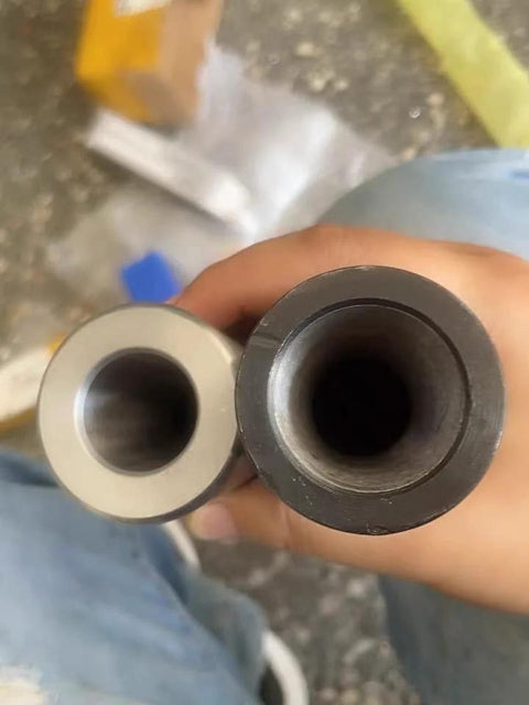 Front view of two Morse taper reducing drill sleeves gray and black held in hand.