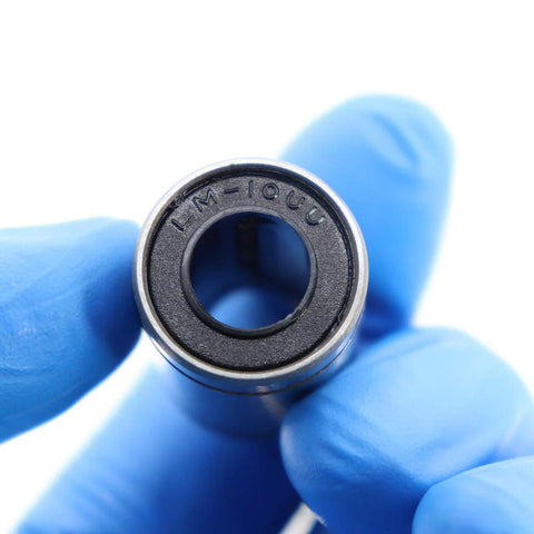 Close-up view of LM10UU linear bearing (10x19x29 mm) held by gloved fingers