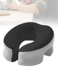 Black and light gray memory foam desk napping pillow with removable cover, shown on a desk next to a napping person.