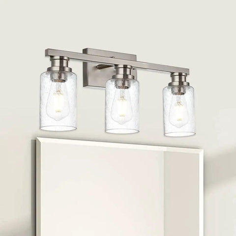 Three Light Wall Mount Bathroom Light Fixture In Brushed Nickel Finish With Seeded Glass Shade above a mirror