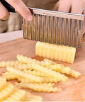 Crinkle cutter with stainless steel wavy blade; side view slicing potatoes into fries