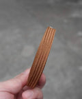 Close-up of Pro Grade Synthetic Silk Tsuka Ito Wrapping Cord 22.9ft in brown, held by a hand, showing texture and thickness.